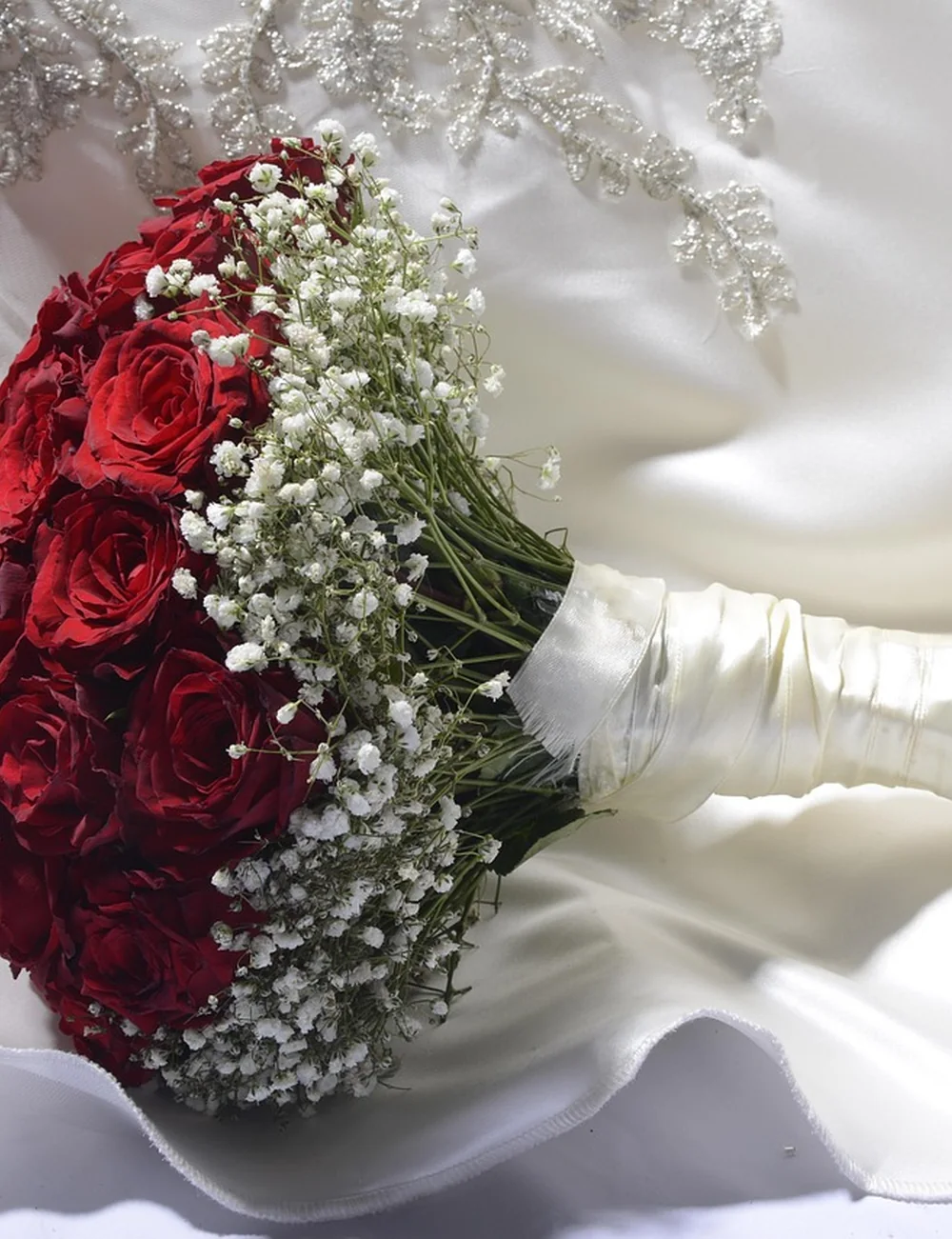 Détail couture avec roses rouges, satin blanc et broderies