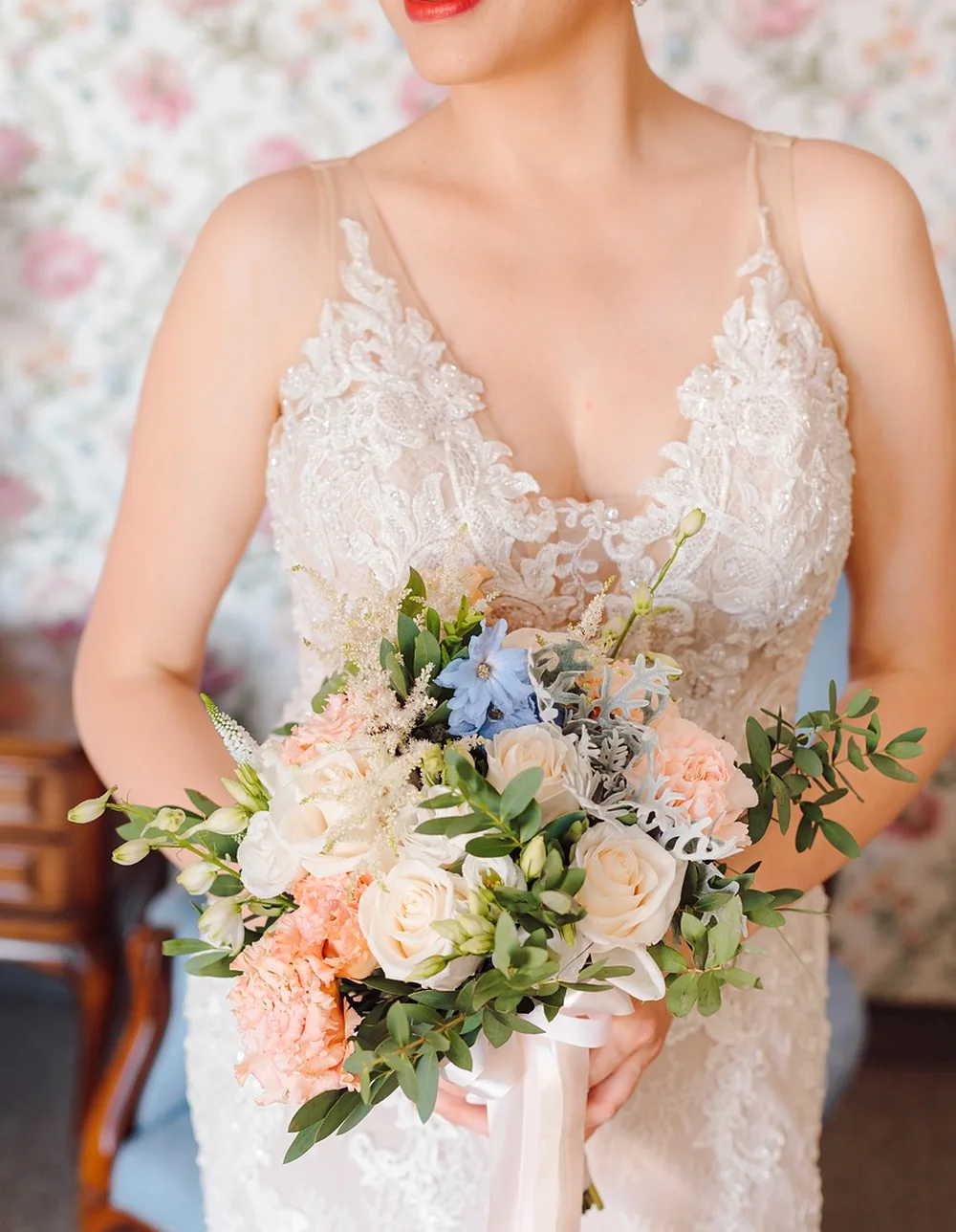 Mariée en robe de dentelle avec bouquet aux tons pastel